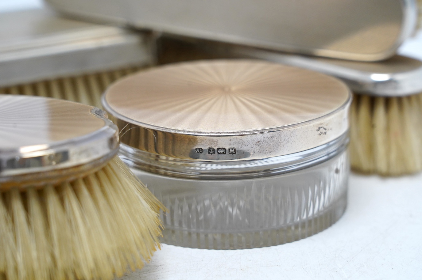Nine assorted mid 20th century silver mounted dressing table items including a hand mirror, brush and powder jar with enamel, jar diameter 86mm. Condition - poor to fair